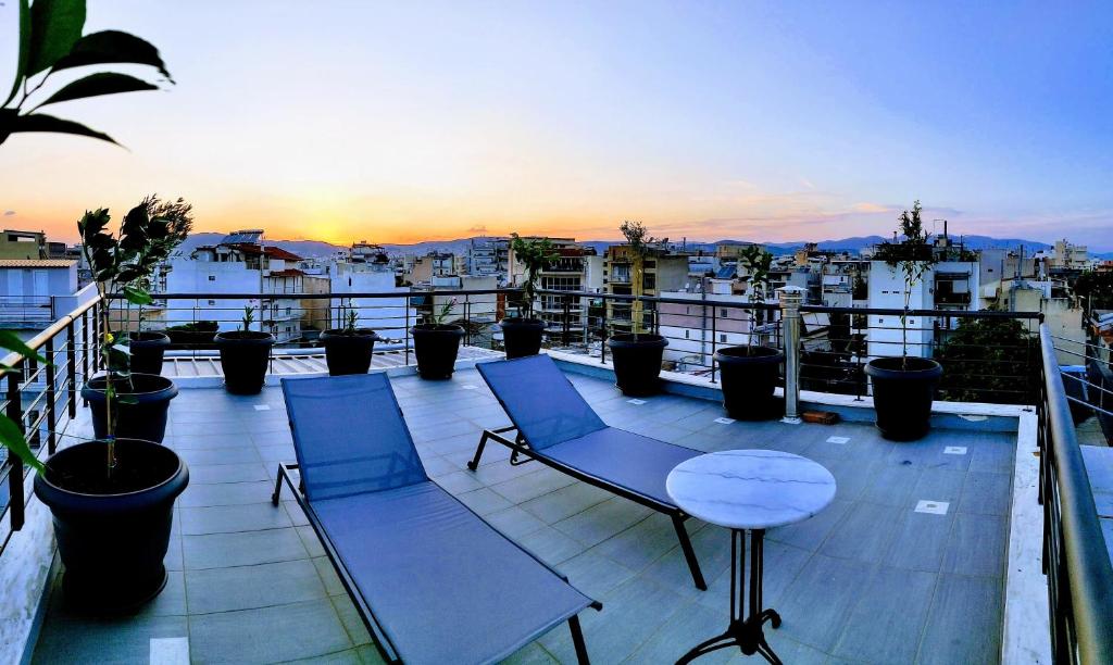 a balcony with two chairs and a table and a sunset at Elegant Bright Apartment with Acropolis view terrace in Athens
