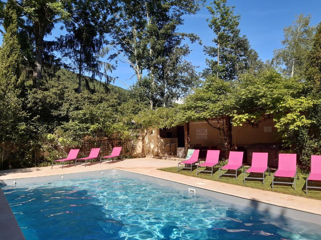 a swimming pool with pink lounge chairs and a swimming pool at Gîtes du Hameau Baylesse in Saint-Jean-dʼAigues-Vives