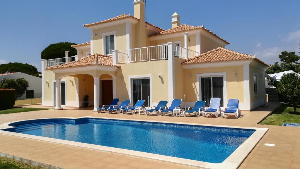 a villa with a swimming pool in front of a house at Villa 48 in Quarteira