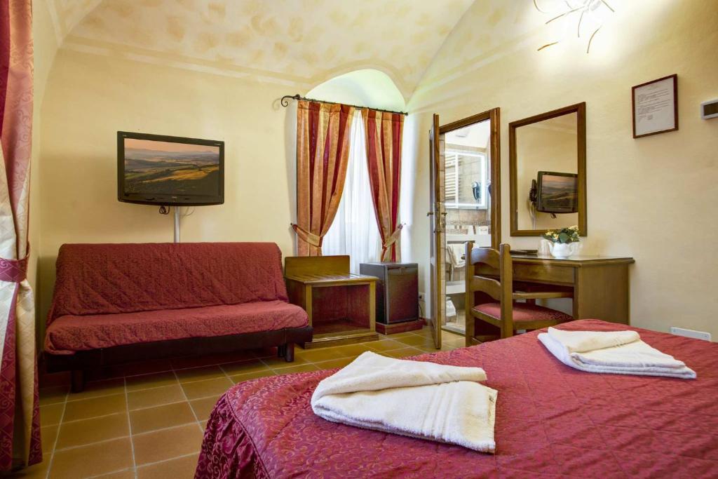 sypialnia z 2 łóżkami, kanapą i lustrem w obiekcie Hotel Residence Villa Rioddi w mieście Volterra