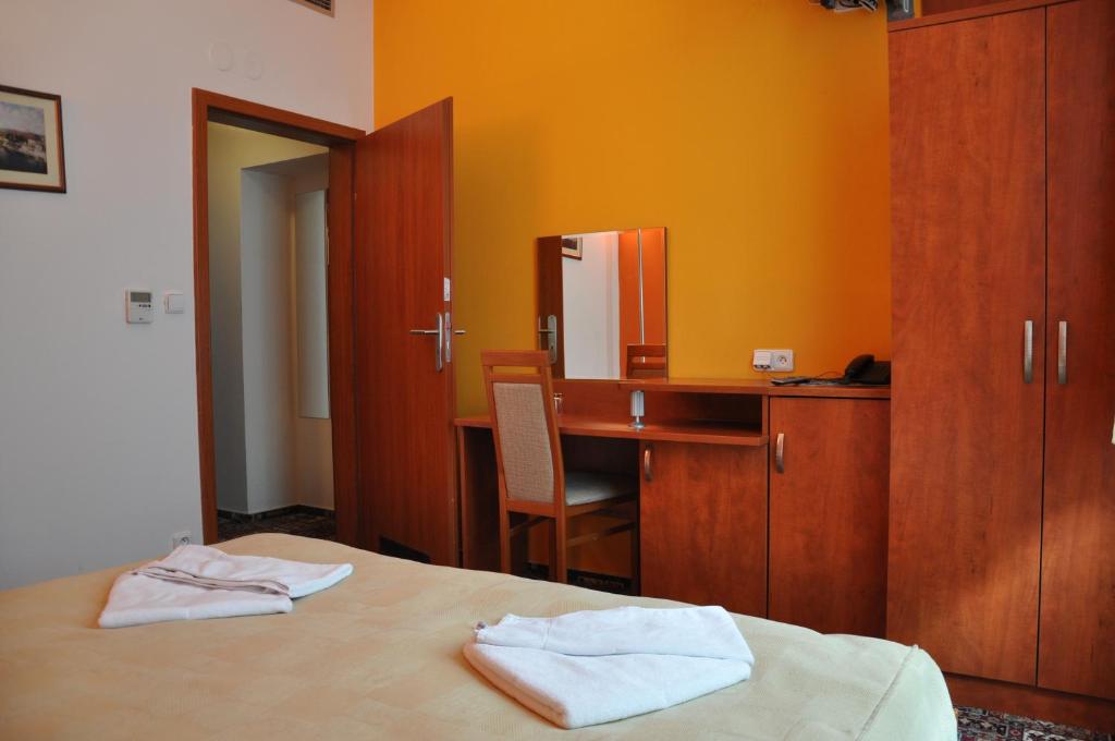 a bedroom with a desk and a bed with towels at City Central De Luxe in Prague