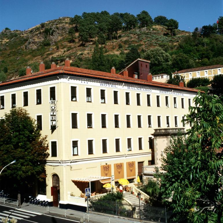 a large white building with a mountain in the background at Gran Hotel Balneario in Baños de Montemayor