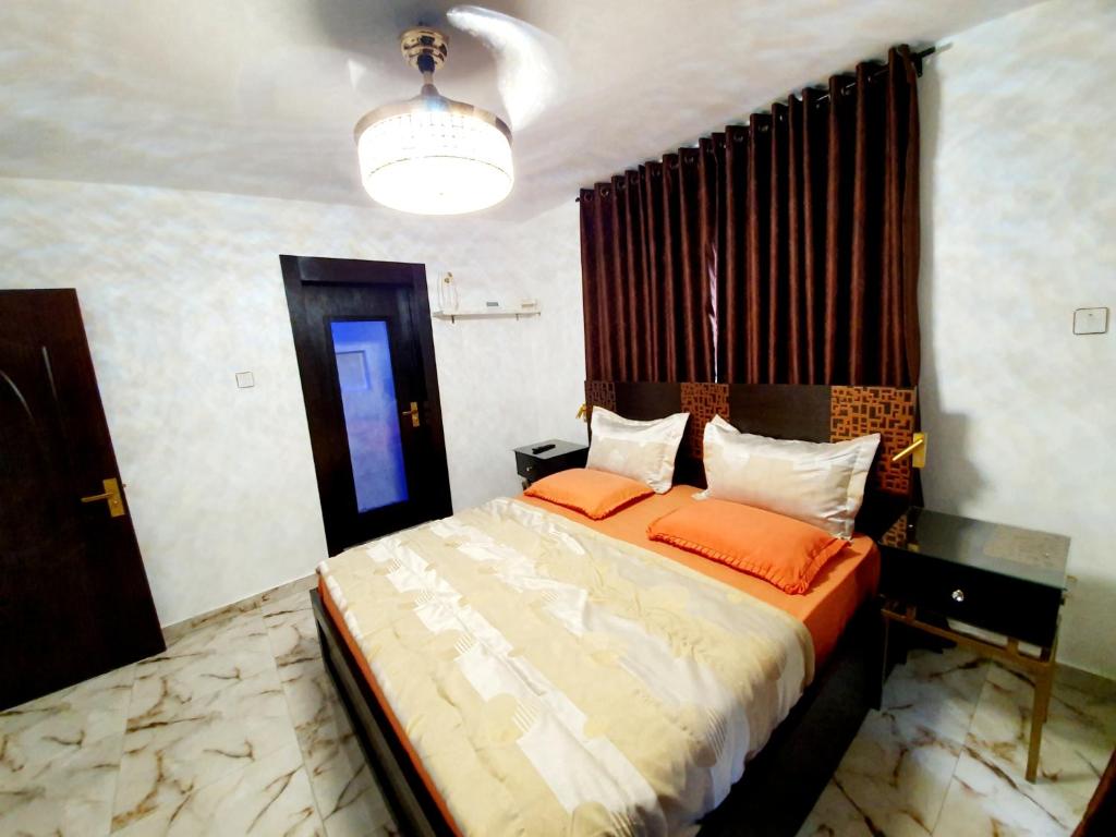 ein Schlafzimmer mit einem Bett mit orangefarbenen Kissen in der Unterkunft CG Apartments Metro in Ikeja