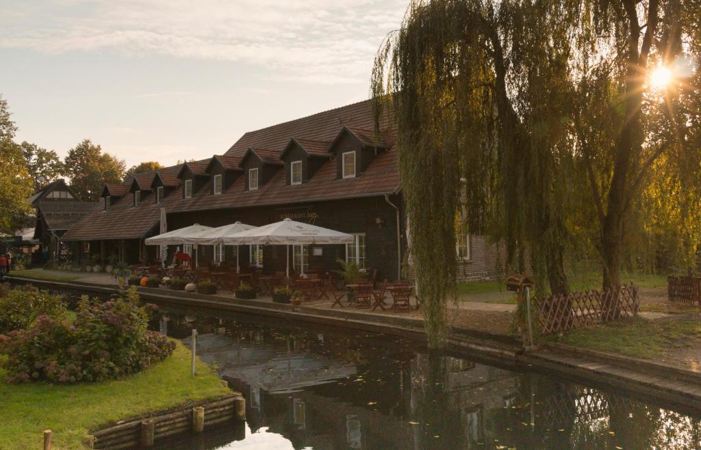 a building with tables and chairs next to a river at Pension an der Dolzke in Kaupen