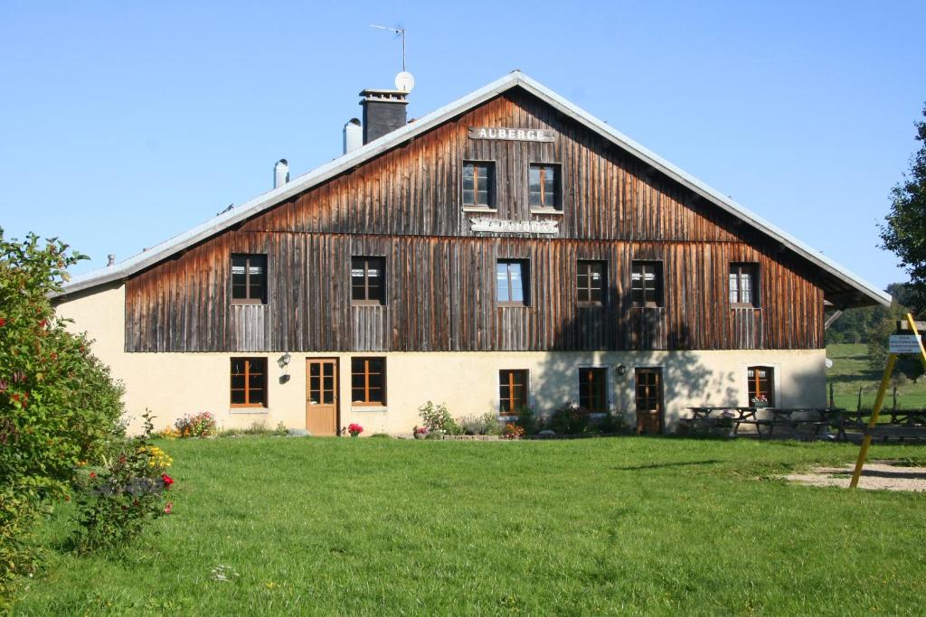 a large wooden barn with a grassy yard at Auberge de la Perdrix in Hauterive-la-Fresse