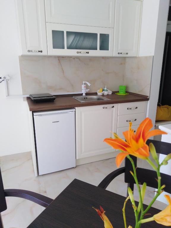 a kitchen with white cabinets and a table with a flower at Apartmani MITIĆ in Veliko Gradište