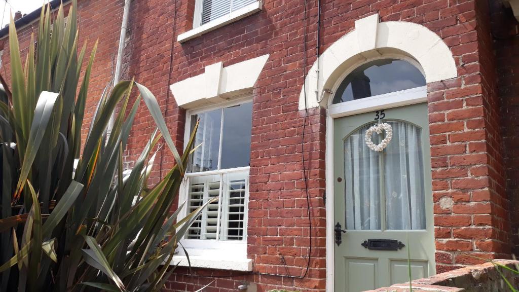 ブリッドポートにあるAllington Hill-Bridport, Dorsetの緑のドアと窓のあるレンガ造りの家