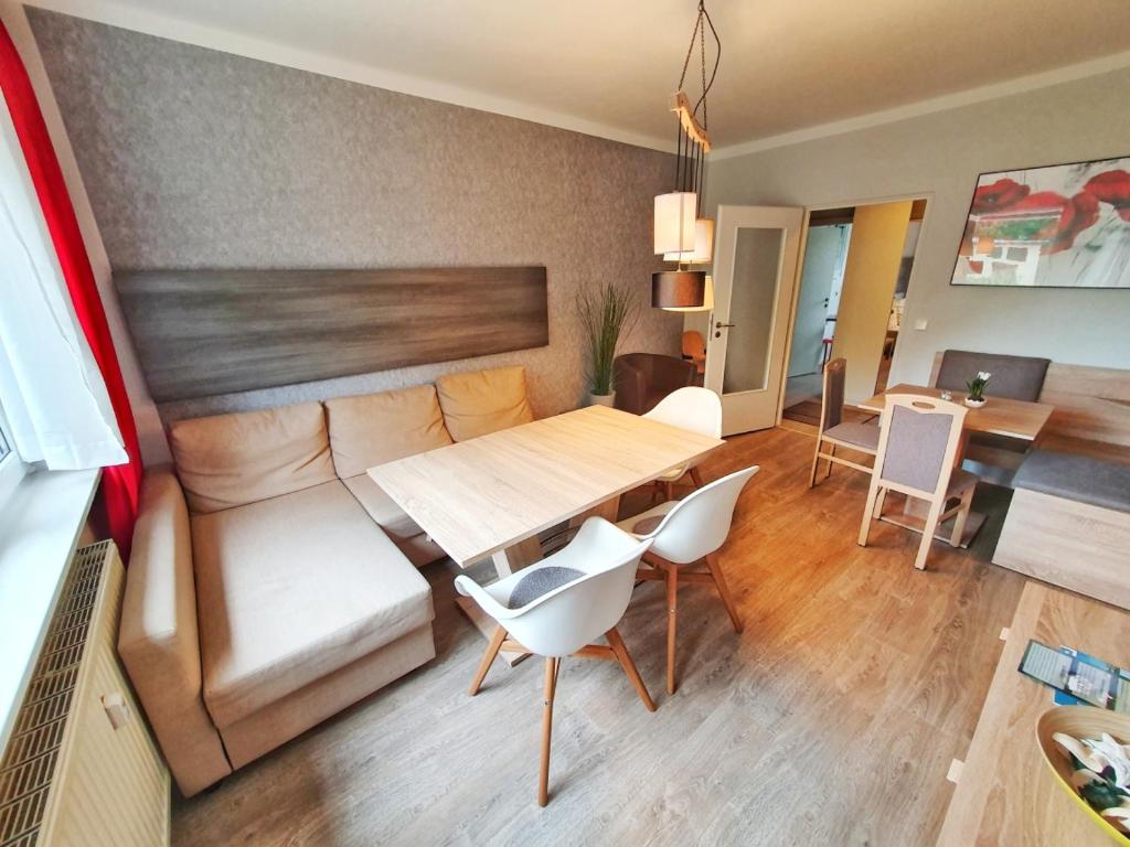 ein Wohnzimmer mit einem Sofa, einem Tisch und Stühlen in der Unterkunft Komfort Ferienwohnungen Zwenkauer See in Zwenkau