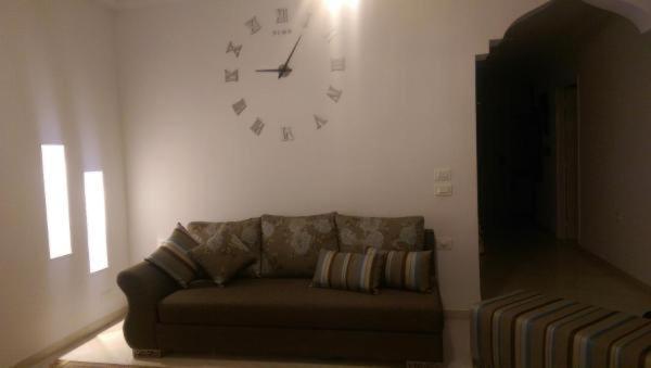 a living room with a couch and a clock on the wall at Belle Maison in Hammamet
