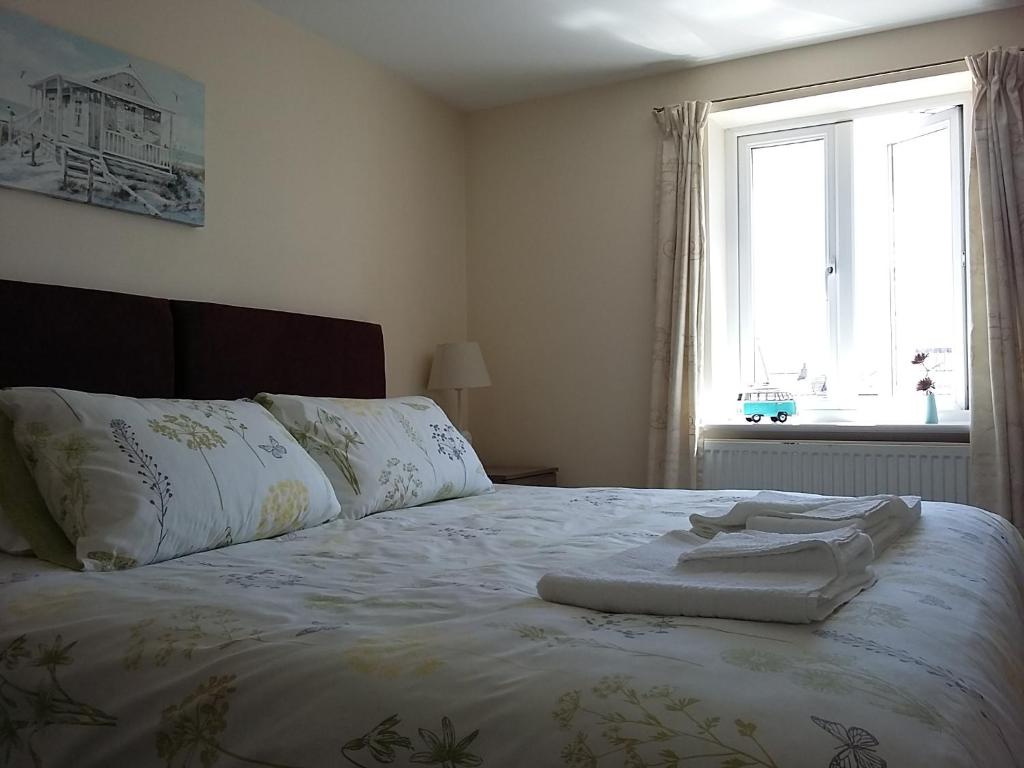 a bedroom with a bed with white sheets and a window at Harrington Flats in Newquay