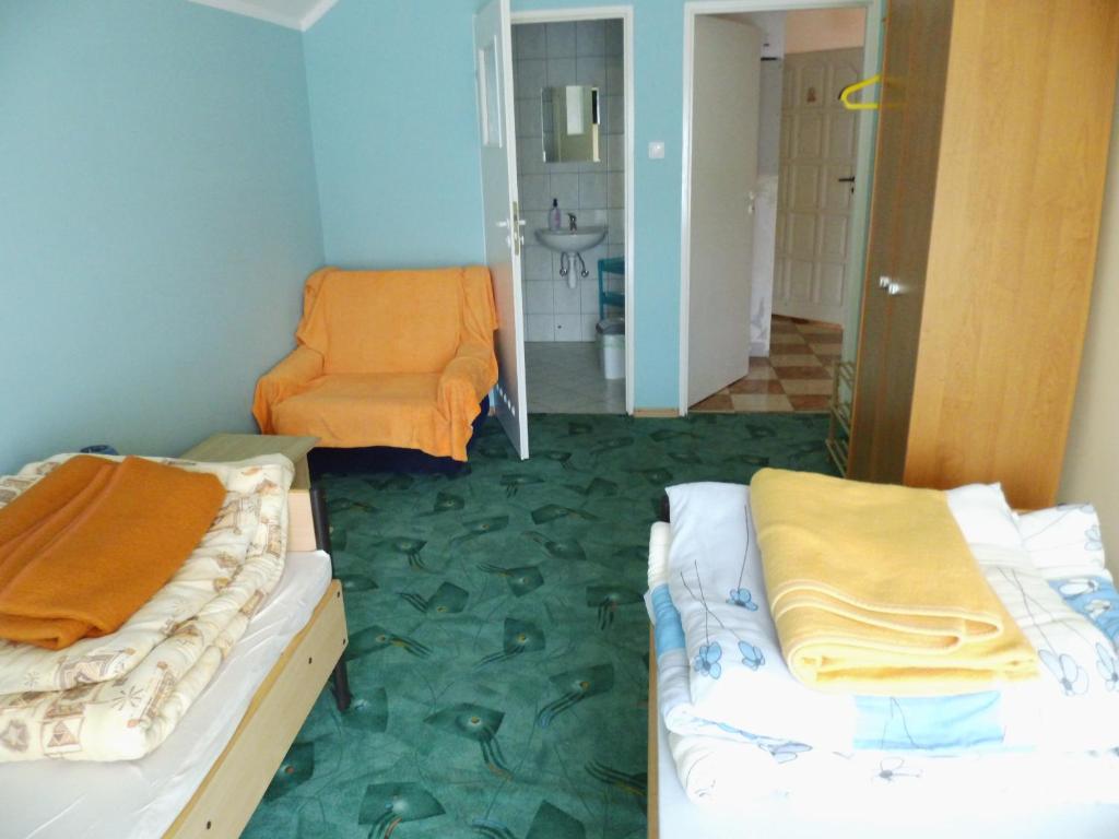 Cette chambre comprend deux lits et une chaise orange. dans l'établissement Kwatera do wynajęcia, à Gołdap