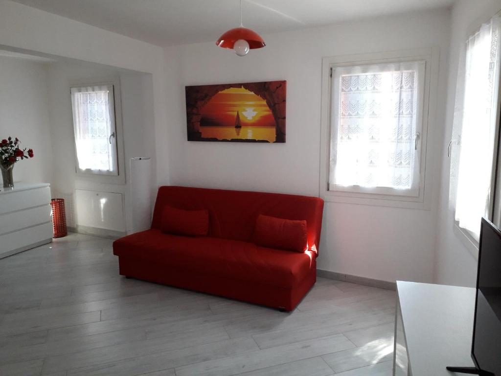 a red couch in a living room with two windows at ANGOLO DI LUCE in Chioggia