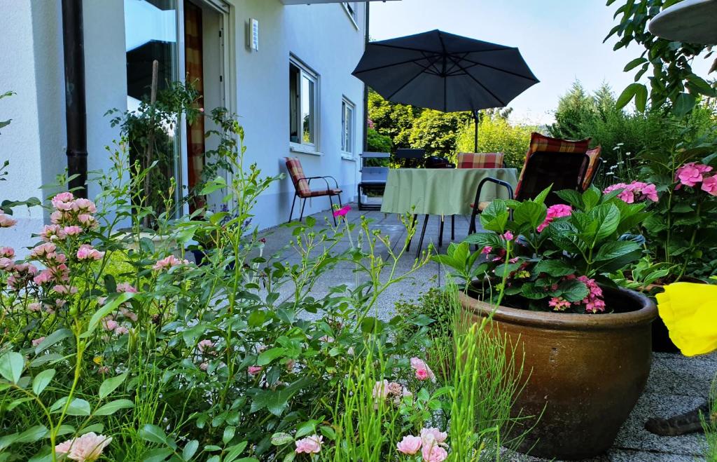 a patio with a table with an umbrella and flowers at Urlaubs(t)raum in Heiligkreuzsteinach