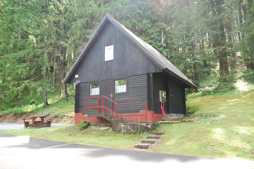 a small black cabin with a red porch in the woods at Chata Brestová,Zuberec in Zuberec