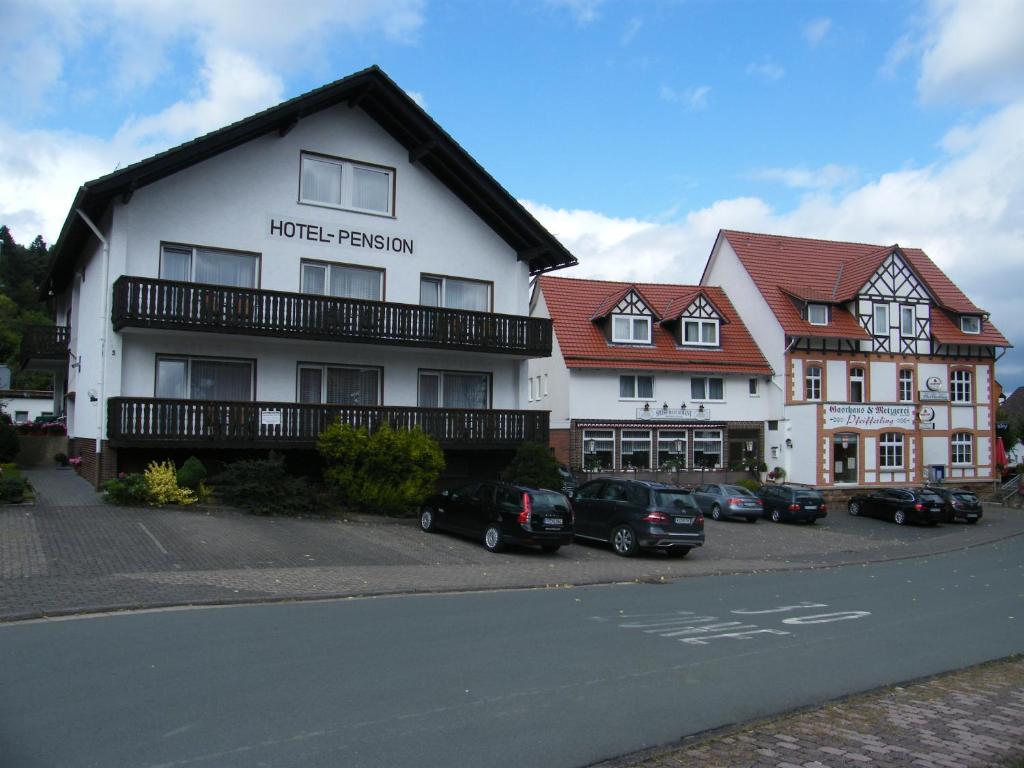 un bâtiment blanc avec des voitures garées devant lui dans l'établissement Gasthaus Hotel Pfeifferling, à Wolfhagen