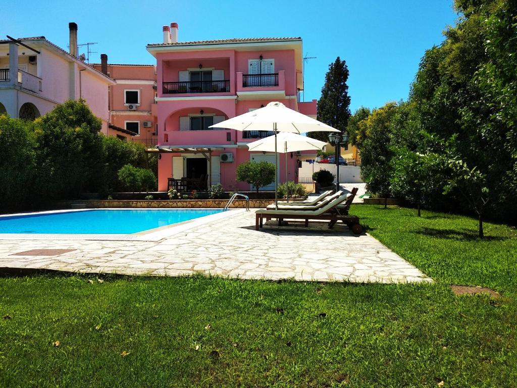 - une piscine avec un banc et un parasol à côté d'une maison dans l'établissement CHA Nanakas Village Inn, à Corfou