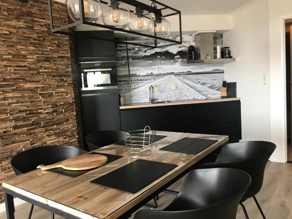 une salle à manger avec une table en bois et des chaises noires dans l'établissement Residentie Hydro Palace, Zeedijk 250!, à Ostende