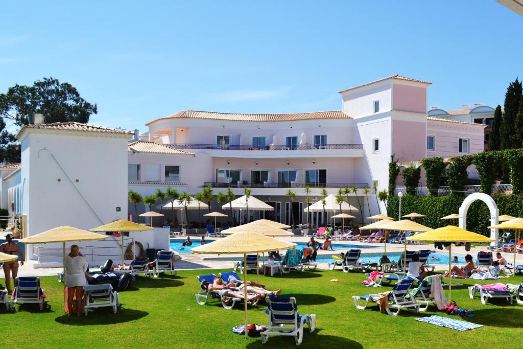 un groupe de personnes assises sur l'herbe près d'un hôtel dans l'établissement Vila Rosa Flat, à Portimão