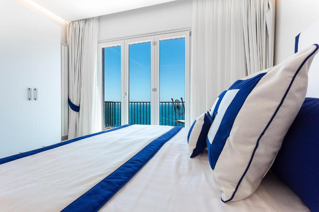 a bedroom with a large bed with blue and white pillows at Hotel Bristol in Vietri sul Mare