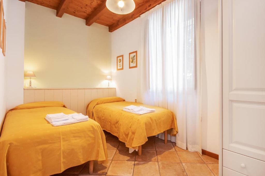 two beds in a room with yellow sheets at Agriturismo La Filanda in Manerba del Garda