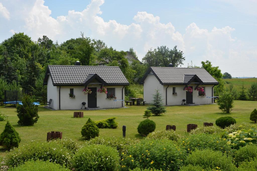 two white houses in a field with a garden at Domki "Bociania Ostoja" in Mikołajki