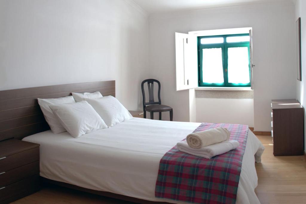 1 dormitorio con 1 cama con sábanas blancas y ventana en Casa da Praça, en Torre de Moncorvo
