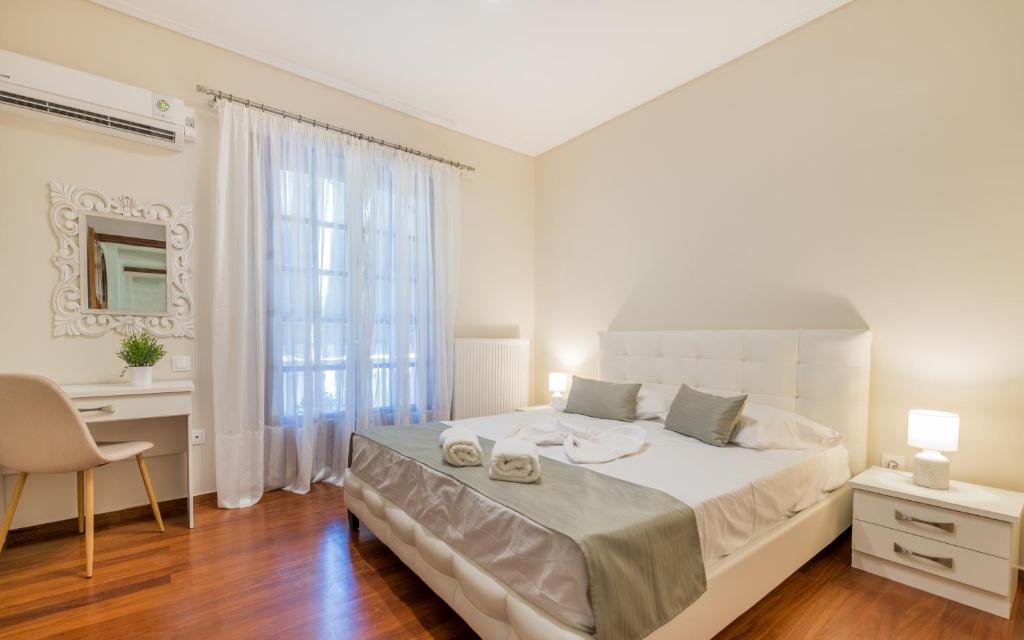 a white bedroom with a large bed and a desk at QUARTA DOWNTOWN HOUSE in Zakynthos Town