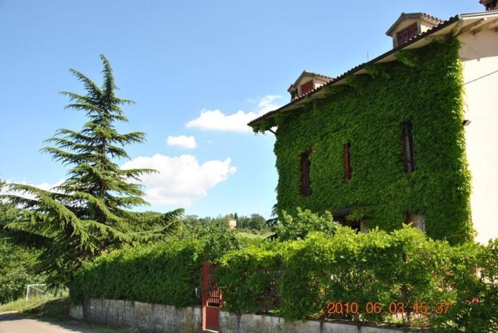 un edificio cubierto de hiedra con un árbol en el fondo en B&B La vecchia quercia Home Restaurant, en Fornovo di Taro