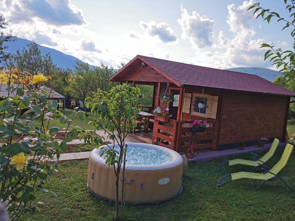 a hot tub in the grass next to a small house at Cottage La Sierra with JACUZZI in Korenica