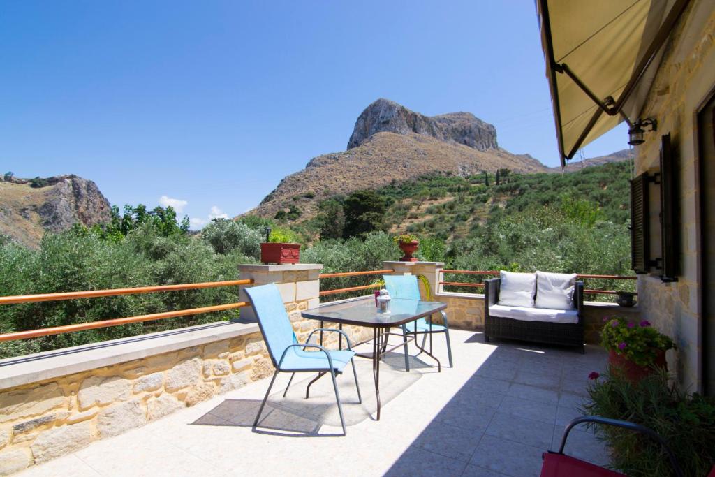 un patio con mesa, sillas y montañas en Mansion Rokka with BBQ and Fireplace, en Kissamos