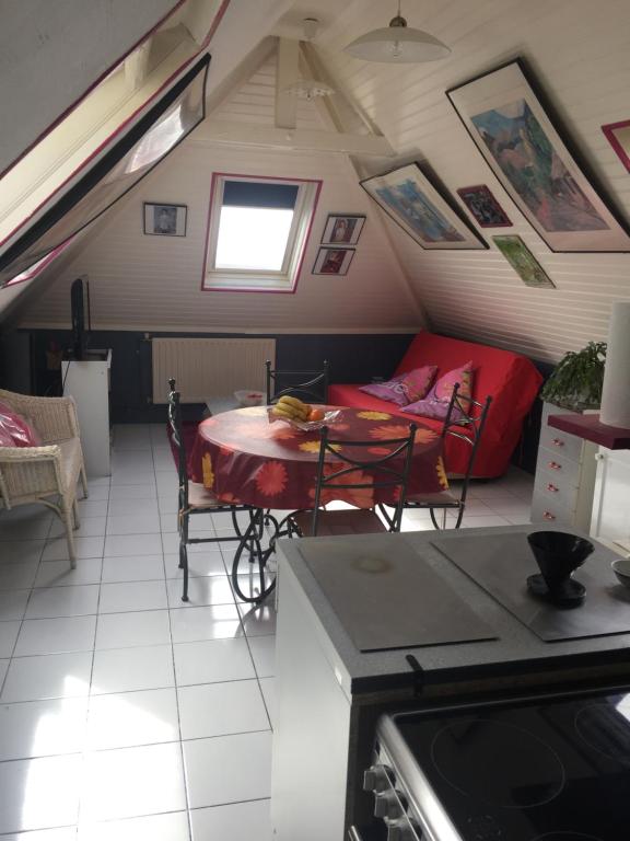 Cette chambre mansardée comprend une table et un canapé. dans l'établissement La Mansardière, à Berck-sur-Mer