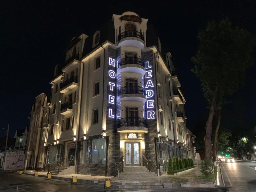a building with a sign on the side of it at night at Leader Hotel in Tashkent