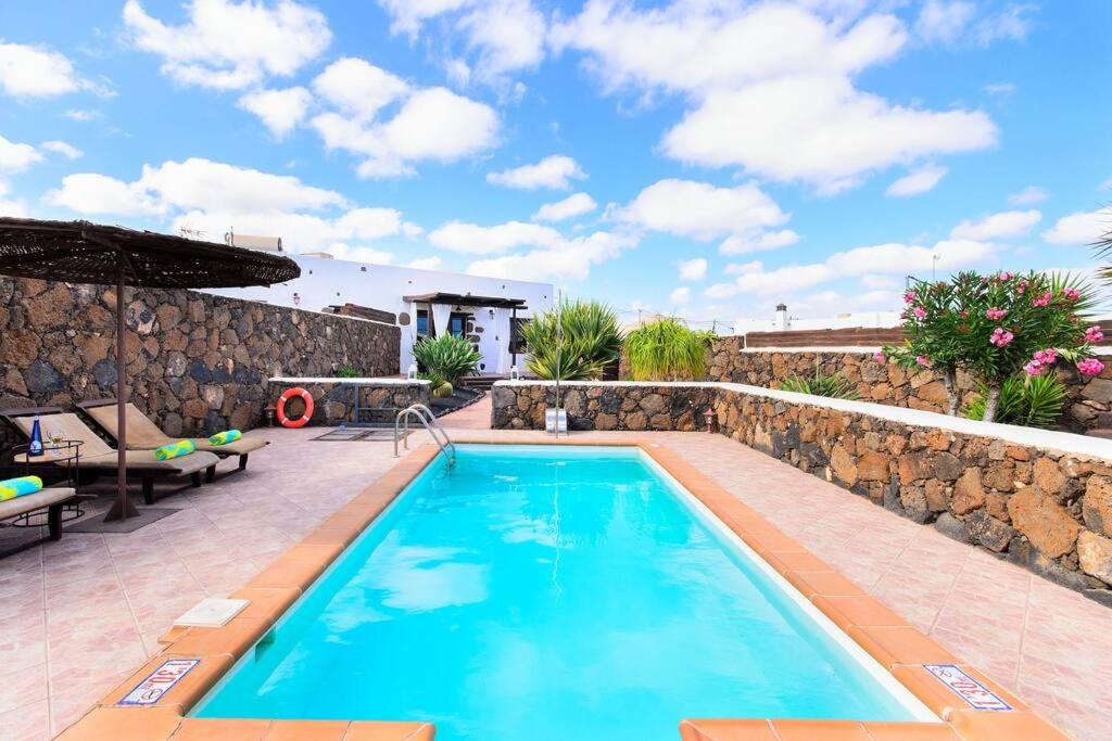 una grande piscina con parete in pietra e un patio di El Caserío de Güime Villa con Piscina Climatizada a San Bartolomé