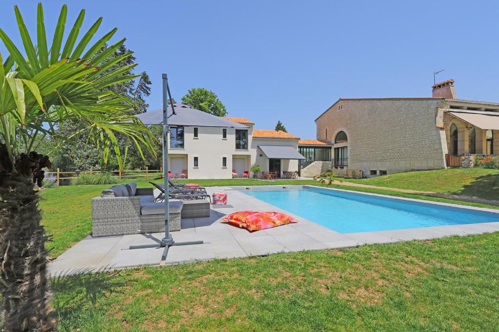 una piscina con sofá y una silla junto a una casa en L Esprit du Clain chambres d hôtes BandB de standing proches du Futuroscope Golf et Lac de St Cyr, en Naintré