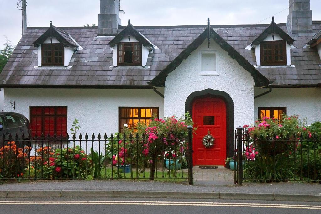 une maison blanche avec une porte rouge et une clôture dans l'établissement Ivy Cottage B&B, à Killarney