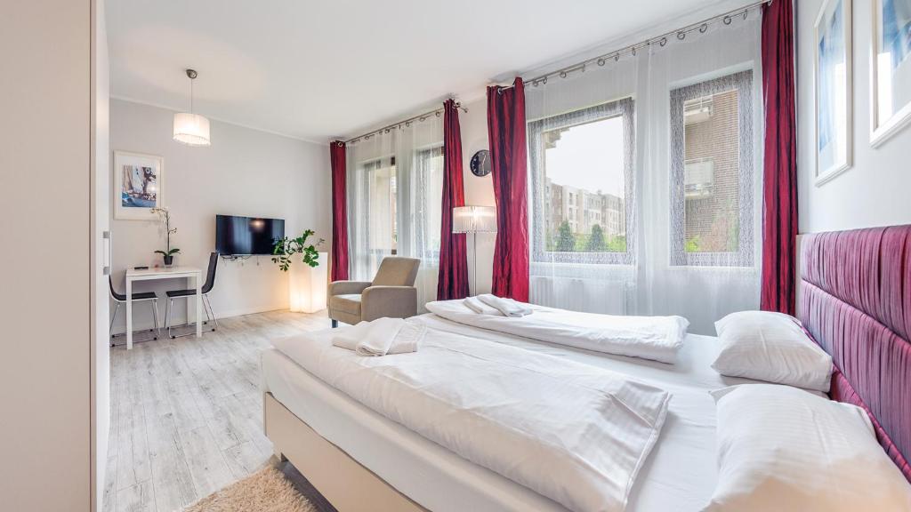 2 camas en un dormitorio con cortinas rojas y escritorio en Sopot Residence - Sea Deluxe apartment B, en Sopot