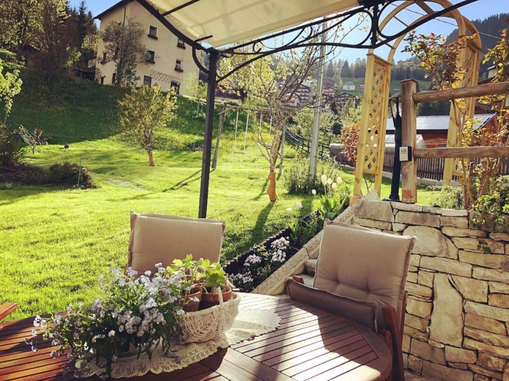 een patio met 2 stoelen en een tafel met bloemen bij Dolomites Charme Chalet in Colle Santa Lucia