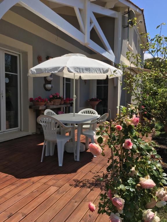 a patio with a table and chairs and an umbrella at Chambres d'Hôtes d'Aliénor in Soulac-sur-Mer