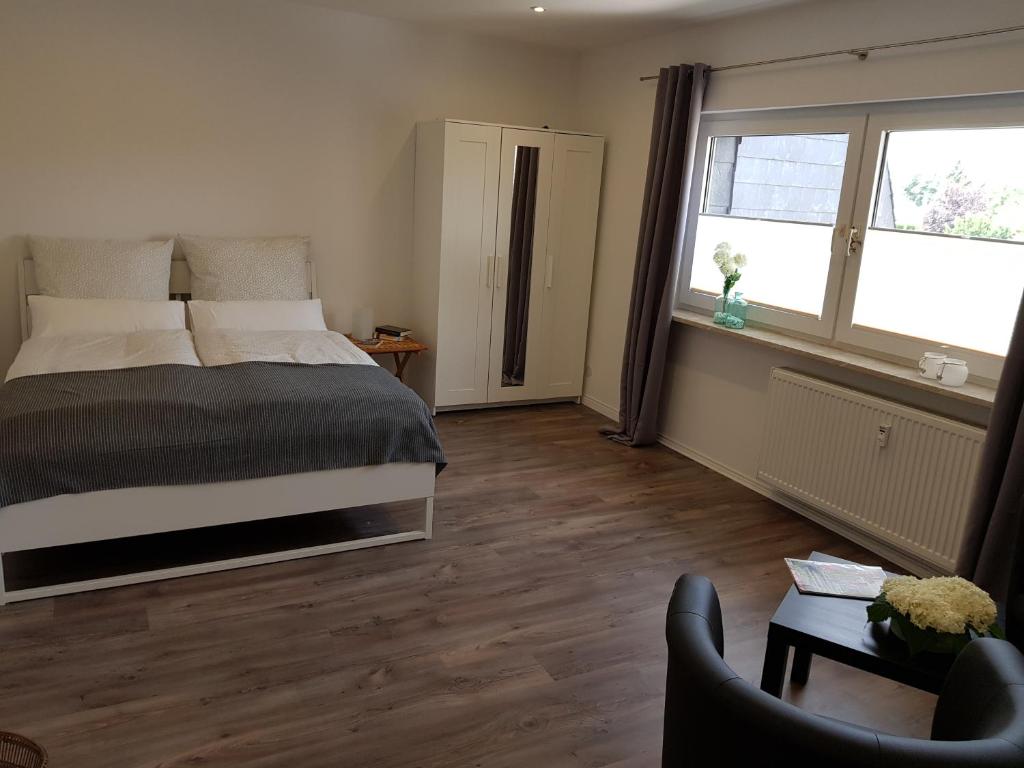 ein Schlafzimmer mit einem Bett, einem Stuhl und einem Fenster in der Unterkunft Ferienappartement Jung in Kamp-Lintfort