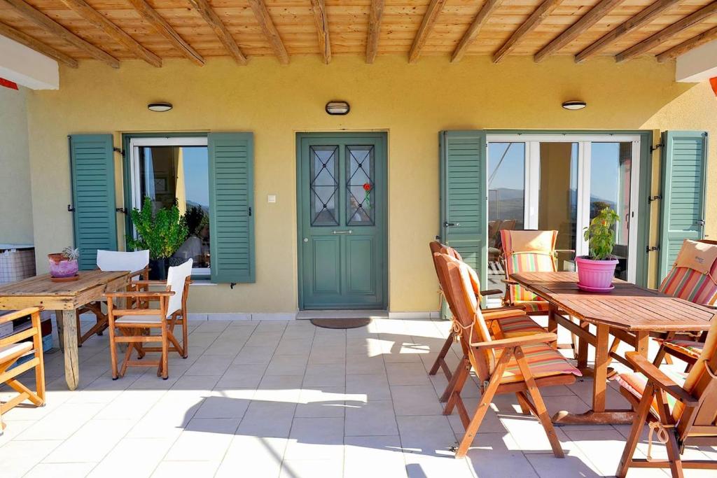 a patio with wooden tables and chairs and a green door at Home in Agros Anna Dimitris in Agrós