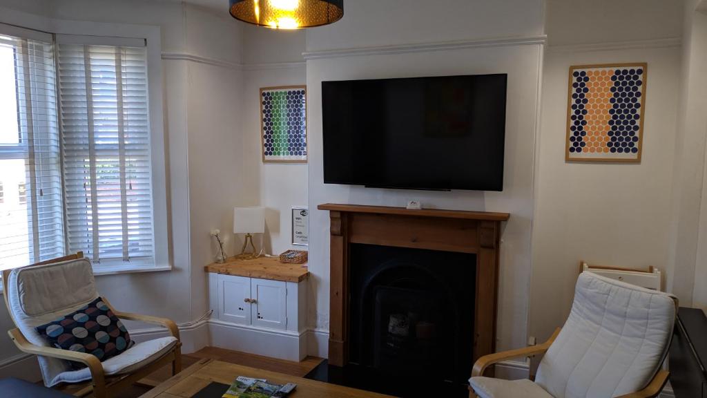 a living room with a fireplace and a flat screen tv at Victoria House in Exeter