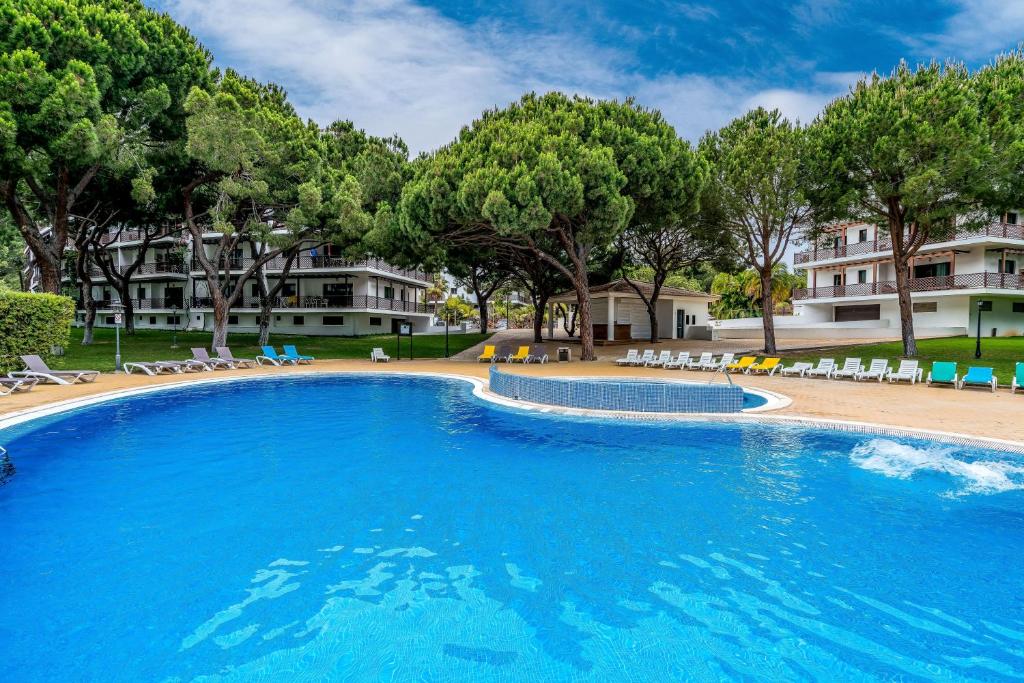 a large swimming pool with chairs and trees at CAROB APARTMENT - BY MAYORAL (FALÉSIA BEACH) in Olhos de Água