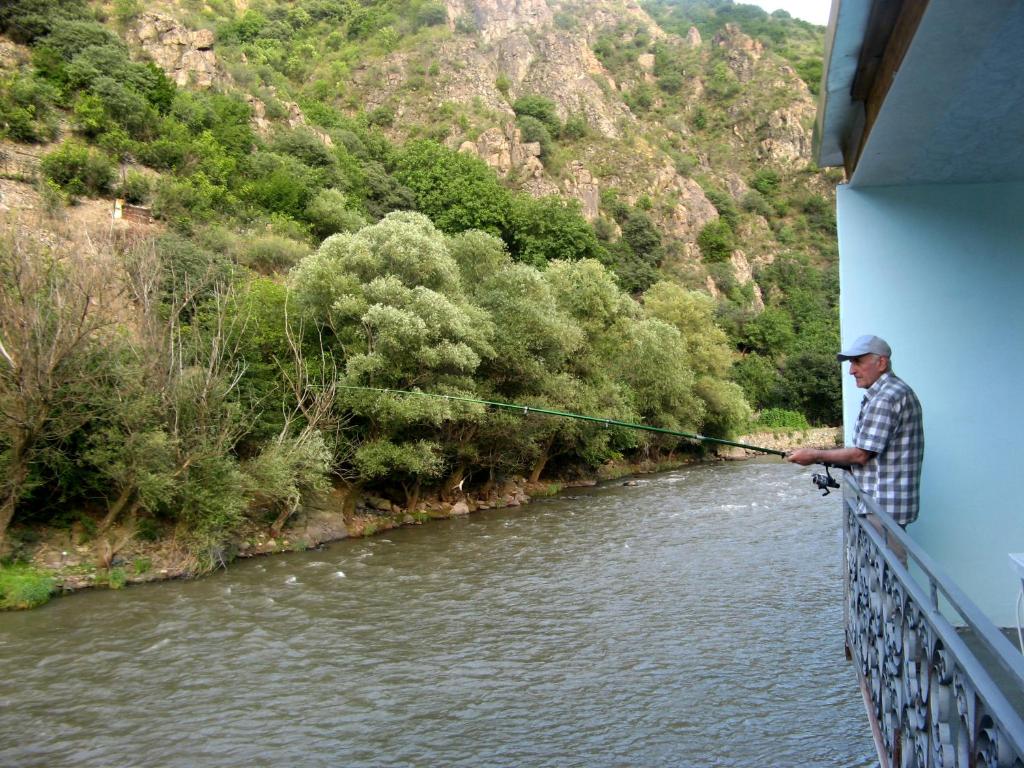 un homme debout sur un pont tenant une canne à pêche dans l'établissement NEW SANAHIN, à Alaverdi