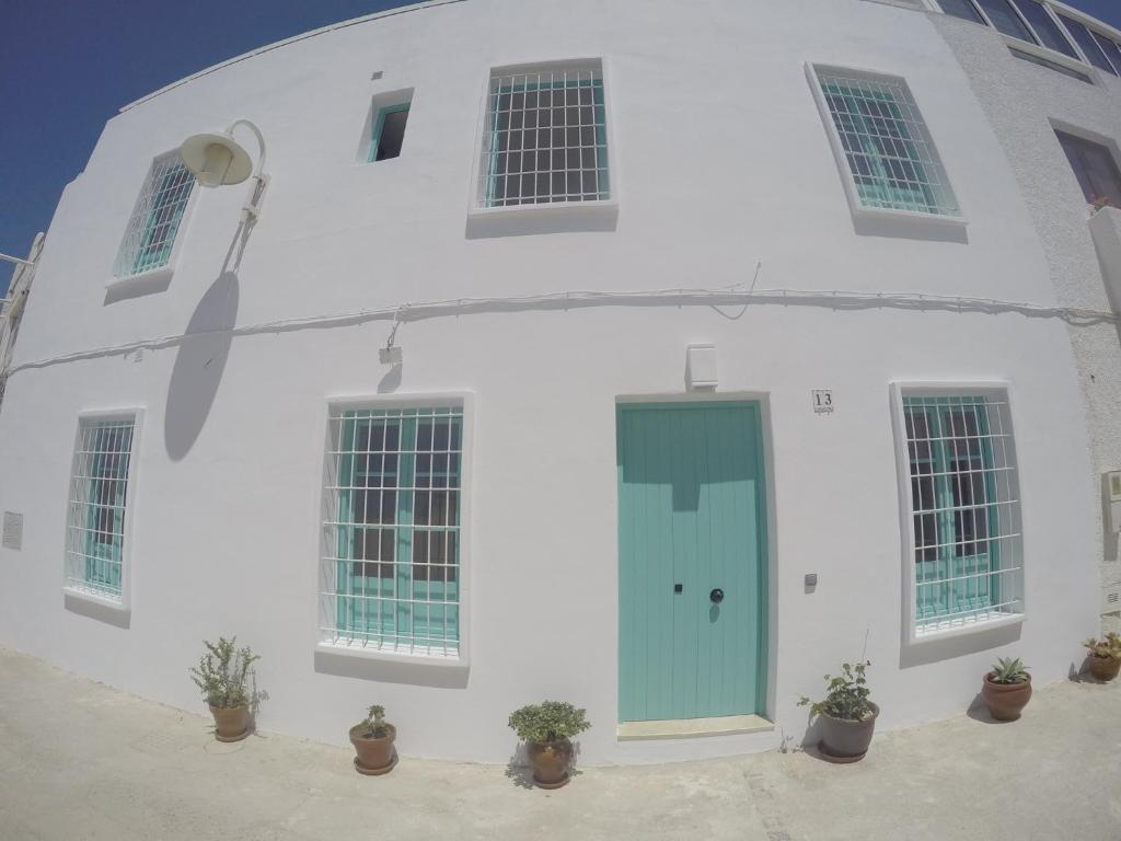 un edificio blanco con una puerta azul en El Chanchullero, en Agua Amarga