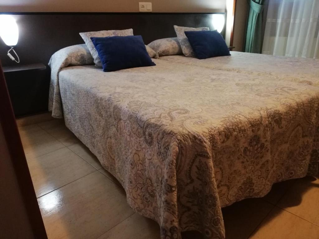 Una cama grande con almohadas azules encima. en Hotel Restaurante Oviedo, en Luarca