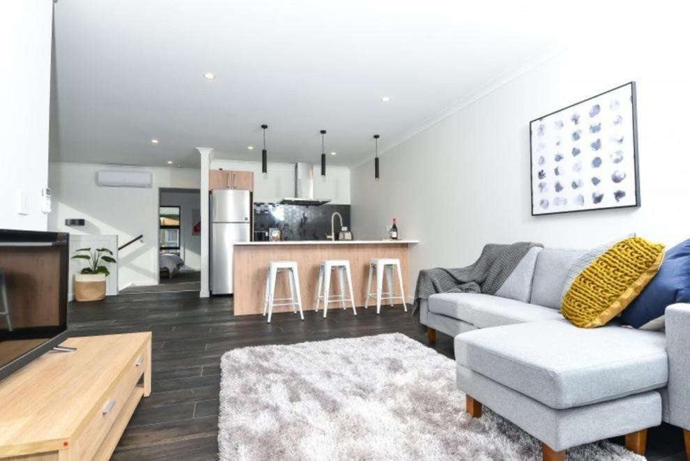 a living room with a couch and a kitchen at Central Park Gemini Apartments in Hamilton