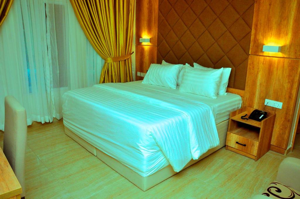 a bedroom with a large bed with white sheets at Lit Suites in Abuja
