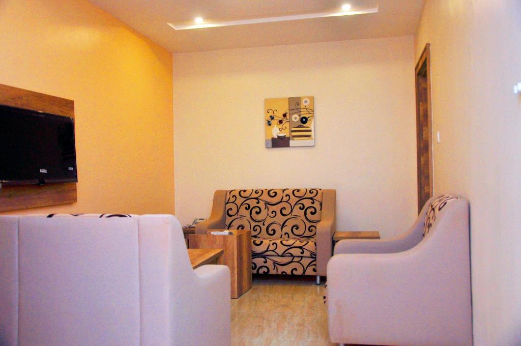 a waiting room with two chairs and a flat screen tv at Lit Suites in Abuja