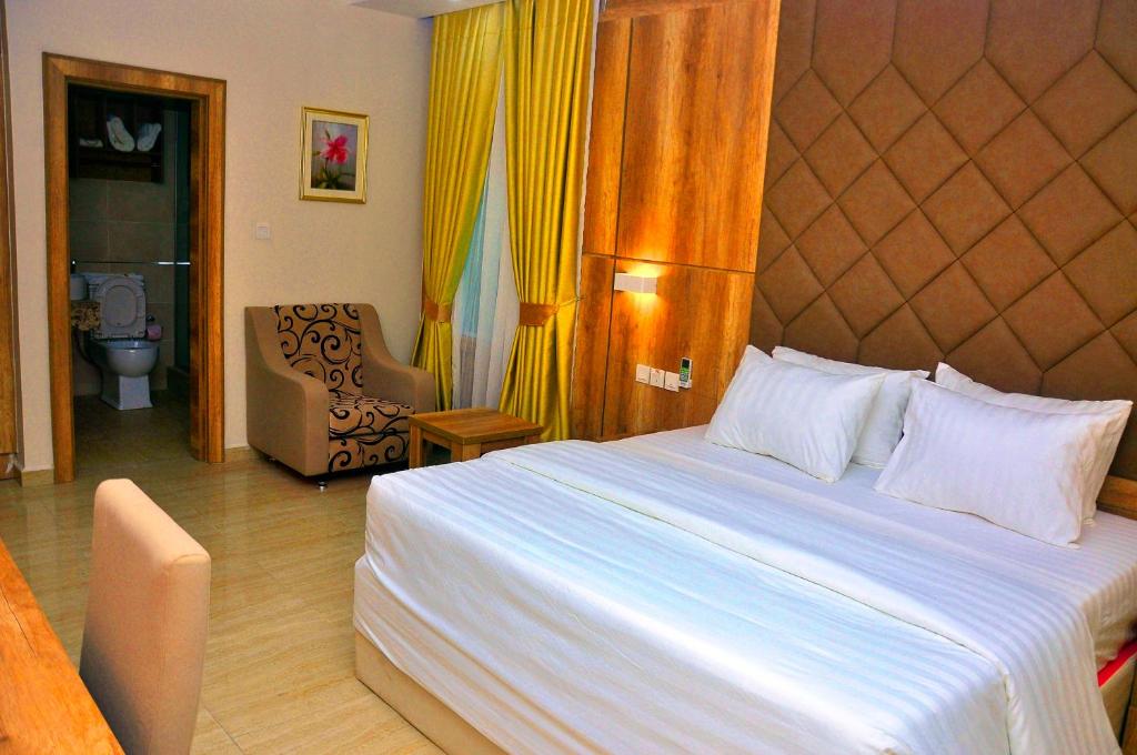 a bedroom with a large bed and a chair at Lit Suites in Abuja