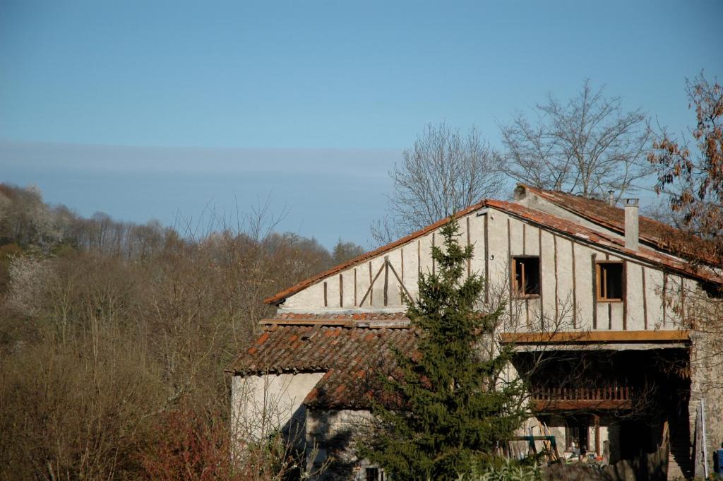 een oud huis met een boom ervoor bij Gîte fermier de Saint-Lizier in Saint-Lizier